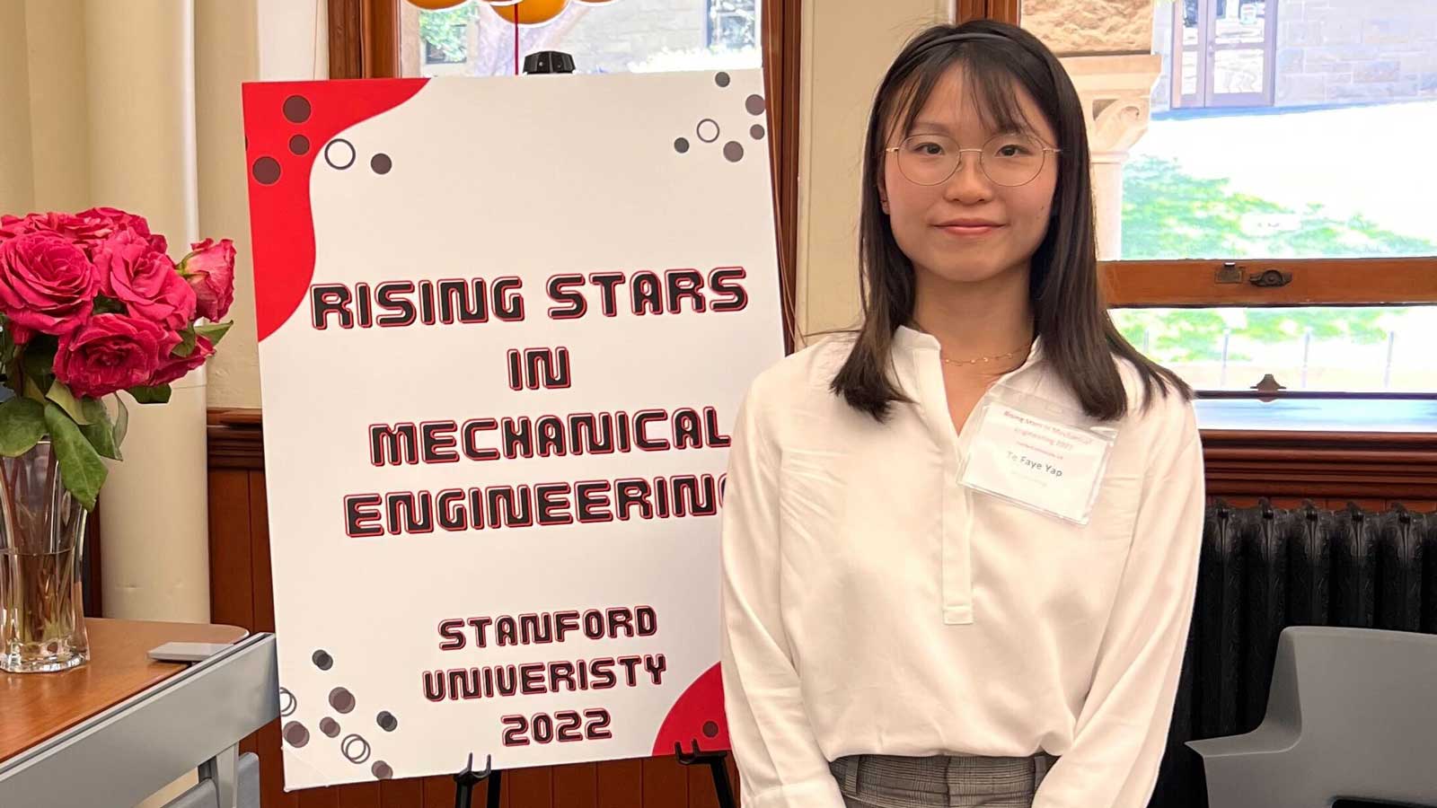 Te Faye Yap stands beside side reading Rising Stars in Mechanical Engineering